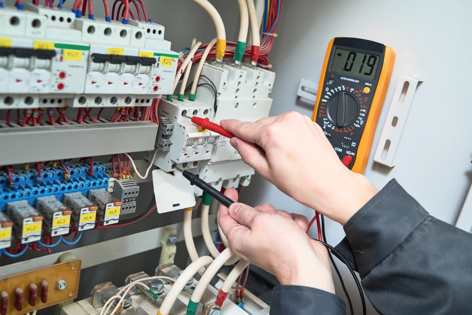 Un électricien effectue des mesures électriques dans un tableau de distribution intérieur